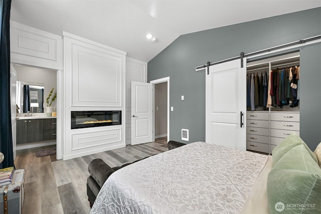 2649 Sandwood Ln, Blaine, WA 98230 - bedroom featuring vaulted ceiling, wood finished floors, a closet, connected bathroom, and a barn door