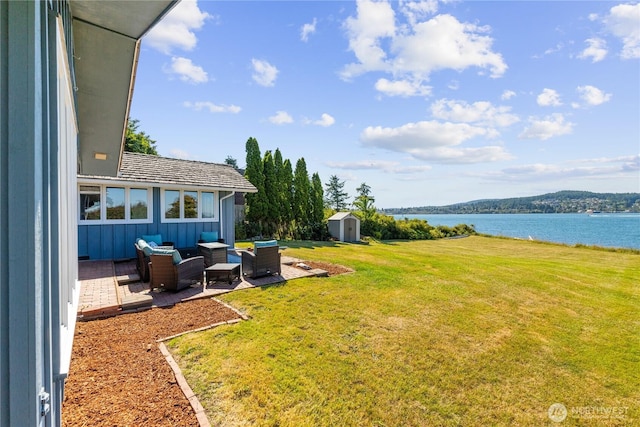 4448 S Shore Dr, Anacortes, WA 98221 - view of green lawn with an outdoor living space, a storage shed, a patio, and a water view