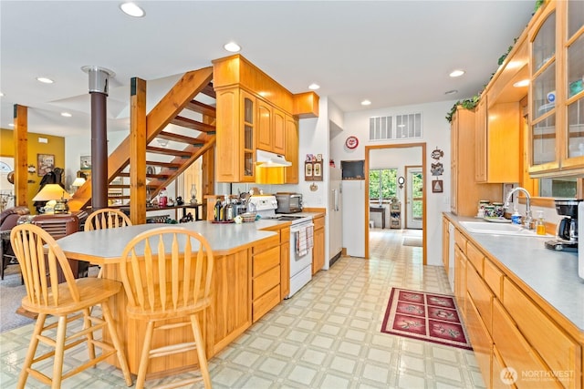 9204 Silver Lake Rd, Maple Falls, WA 98266 - kitchen with white electric range oven, under cabinet range hood, a peninsula, light floors, and a breakfast bar area