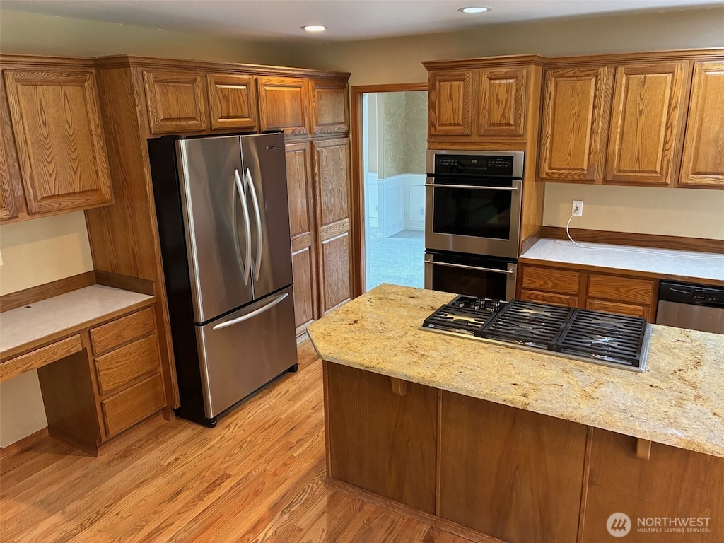 12312 9th St E, Edgewood, WA 98372 - kitchen featuring stainless steel appliances, brown cabinets, light wood-style floors, recessed lighting, and light stone counters
