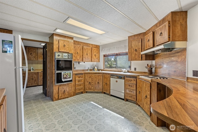 2641 Scotlac Dr SW, Olympia, WA 98512 - kitchen with white appliances, brown cabinetry, under cabinet range hood, and light countertops