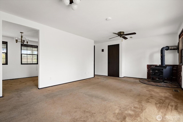 1078 NW Kitsap Ter, Oak Harbor, WA 98277 - unfurnished living room featuring a wood stove, carpet floors, a chandelier, and a ceiling fan
