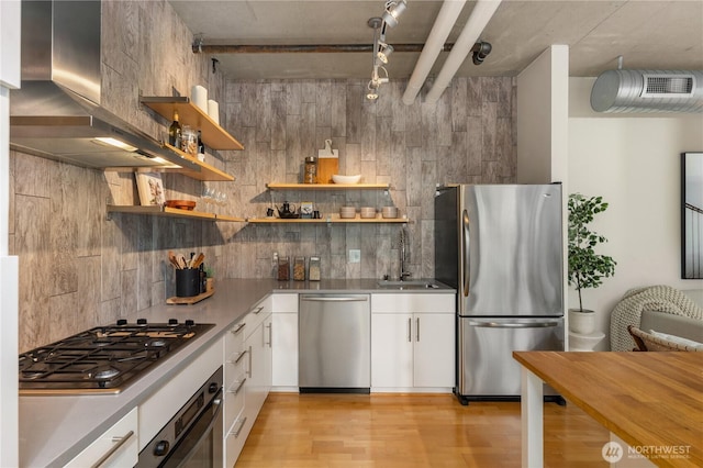 2720 3rd Ave Unit 412, Seattle, WA 98121 - kitchen with appliances with stainless steel finishes, wall chimney exhaust hood, white cabinets, light wood-type flooring, and decorative backsplash