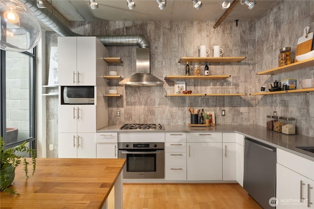 2720 3rd Ave Unit 412, Seattle, WA 98121 - kitchen featuring appliances with stainless steel finishes, wall chimney exhaust hood, open shelves, and wood counters