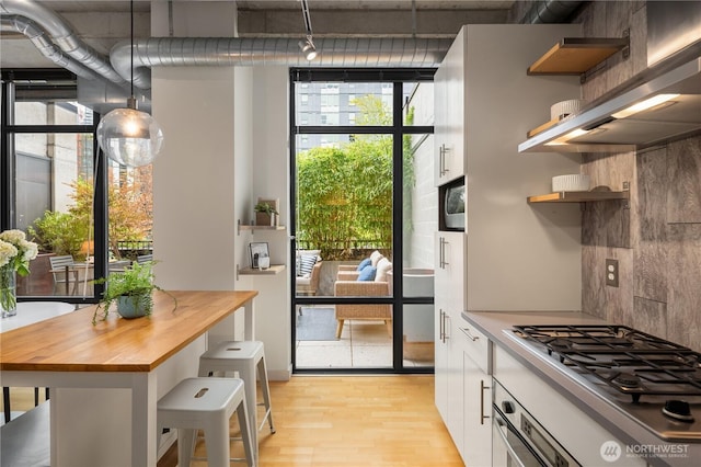 2720 3rd Ave Unit 412, Seattle, WA 98121 - kitchen with open shelves, light wood-type flooring, wooden counters, stainless steel gas stovetop, and decorative backsplash