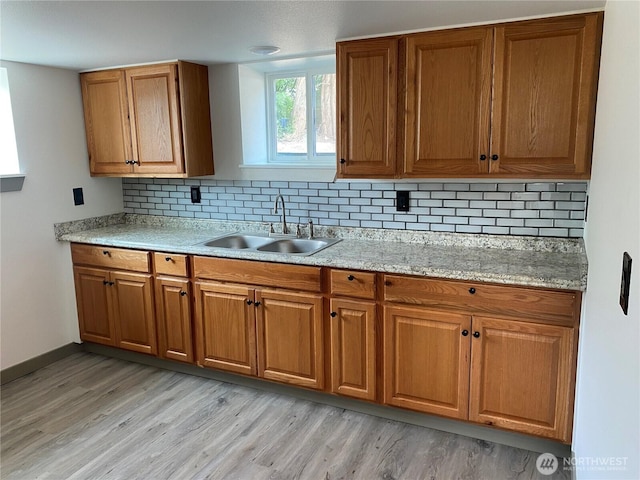 604 SW 4th St, College Place, WA 99324 - kitchen featuring light wood-type flooring, brown cabinets, backsplash, and light stone counters