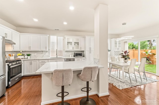 17710 39th Ave SE, Bothell, WA 98012 - kitchen featuring appliances with stainless steel finishes, white cabinets, hardwood / wood-style floors, a kitchen breakfast bar, and recessed lighting