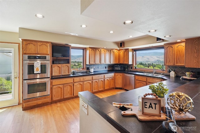 622 Vista View Pl, East Wenatchee, WA 98802 - kitchen featuring brown cabinetry, appliances with stainless steel finishes, light wood finished floors, recessed lighting, and backsplash
