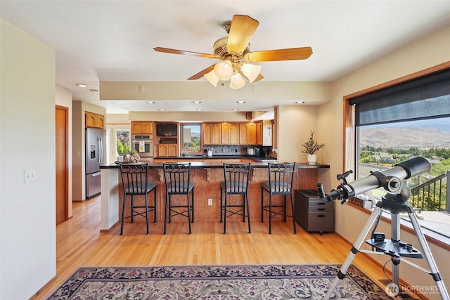 622 Vista View Pl, East Wenatchee, WA 98802 - kitchen featuring a peninsula, dark countertops, light wood-style flooring, and brown cabinets