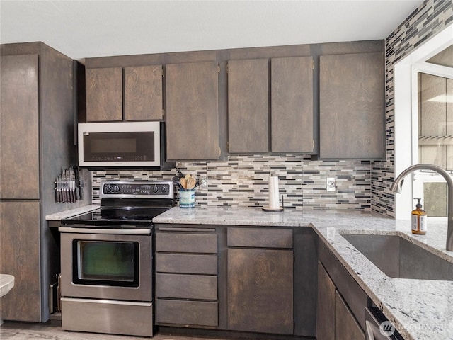 16002 5th Ave E, Tacoma, WA 98445 - kitchen featuring stainless steel appliances, decorative backsplash, light stone countertops, and dark brown cabinets