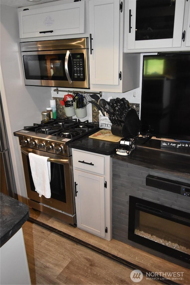 112 Primrose Ln, Cinebar, WA 98533 - kitchen featuring appliances with stainless steel finishes, dark countertops, white cabinets, and wood finished floors