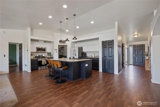 5421 Jackson Ln, Pasco, WA 99301 - kitchen with appliances with stainless steel finishes, dark wood finished floors, dark countertops, a breakfast bar, and white cabinetry