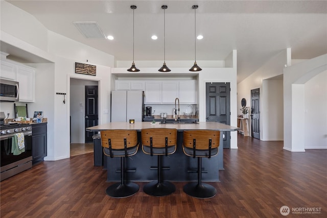 5421 Jackson Ln, Pasco, WA 99301 - kitchen featuring appliances with stainless steel finishes, white cabinetry, dark wood-style flooring, pendant lighting, and a center island with sink