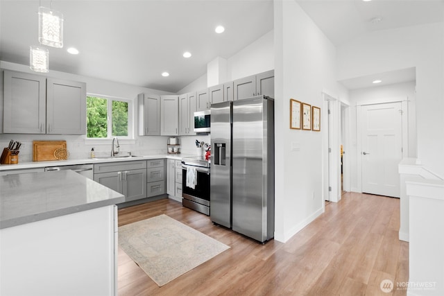 1172 Thorndyke Rd, Port Ludlow, WA 98365 - kitchen with stainless steel appliances, gray cabinets, vaulted ceiling, light wood-style flooring, and pendant lighting