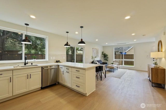 10342 39th Ave NE, Seattle, WA 98125 - kitchen with stainless steel dishwasher, light wood-style flooring, a peninsula, light countertops, and recessed lighting
