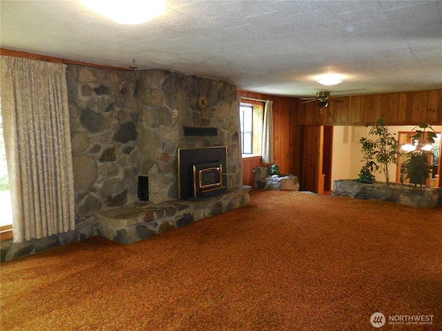 3649 Long Lake Rd SE, Port Orchard, WA 98366 - unfurnished living room featuring carpet flooring, wood walls, a ceiling fan, and a wood stove