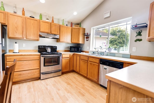 858 Willow Ct SW, Ocean Shores, WA 98569 - kitchen with stainless steel appliances, under cabinet range hood, vaulted ceiling, light countertops, and light wood-style flooring
