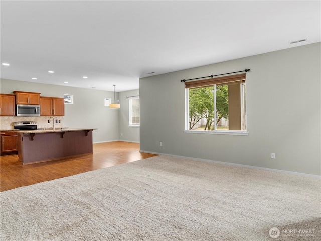 2220 166th St Ct E, Tacoma, WA 98445 - kitchen with appliances with stainless steel finishes, a breakfast bar, brown cabinets, recessed lighting, and open floor plan