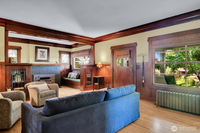 4926 42nd Ave S, Seattle, WA 98118 - living area featuring radiator heating unit, ornamental molding, wainscoting, a brick fireplace, and light wood finished floors
