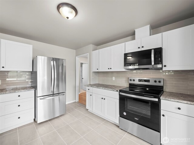 4510 N 24th St, Tacoma, WA 98406 - kitchen with appliances with stainless steel finishes, decorative backsplash, white cabinetry, light tile patterned flooring, and light stone countertops