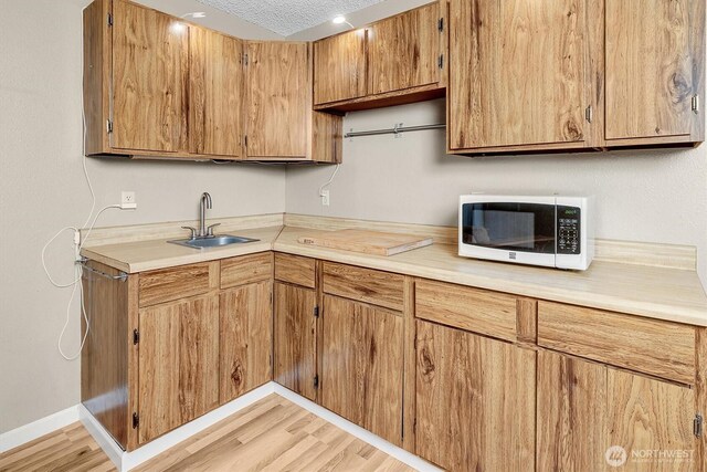 6713 128th Ave SE, Bellevue, WA 98006 - kitchen with white microwave, light countertops, light wood-style floors, brown cabinetry, and a textured ceiling