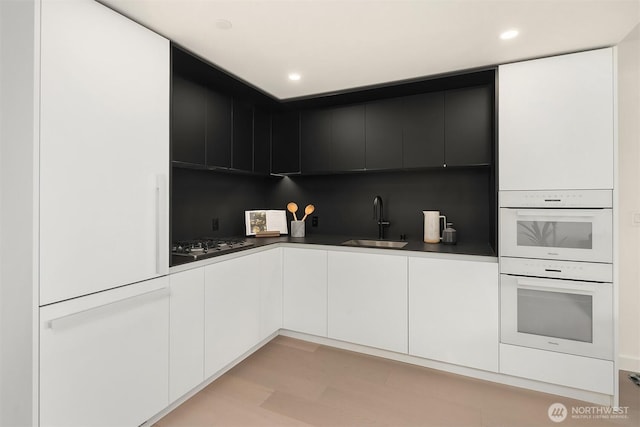 300 Virginia St Unit 1311, Seattle, WA 98101 - kitchen with gas cooktop, modern cabinets, double oven, white cabinetry, and tasteful backsplash