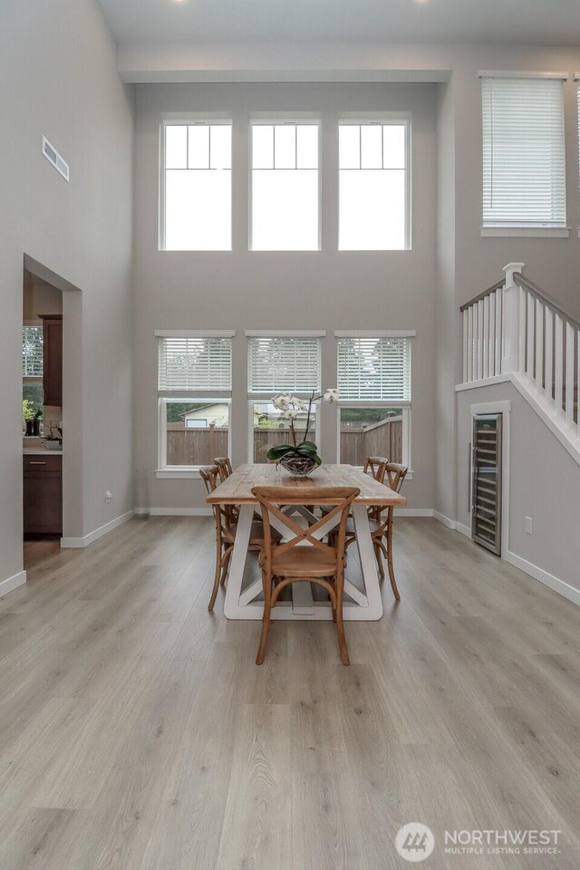 16321 SE 133rd Pl, Renton, WA 98059 - dining room with a towering ceiling, wine cooler, light wood-type flooring, and healthy amount of natural light