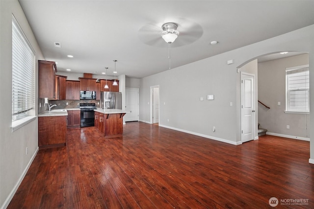 14403 Lockwood Ln SE, Yelm, WA 98597 - kitchen featuring stainless steel appliances, light countertops, ceiling fan, arched walkways, and dark wood-type flooring
