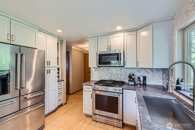 9806 6th Pl SE, Lake Stevens, WA 98258 - kitchen featuring appliances with stainless steel finishes, tasteful backsplash, light wood-style floors, dark stone counters, and recessed lighting