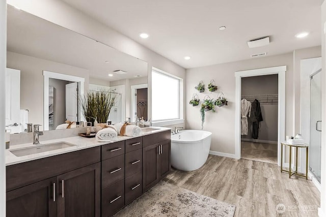16204 SE 133rd Pl Unit 101, Renton, WA 98059 - bathroom with a walk in closet, a shower stall, double vanity, wood finished floors, and recessed lighting