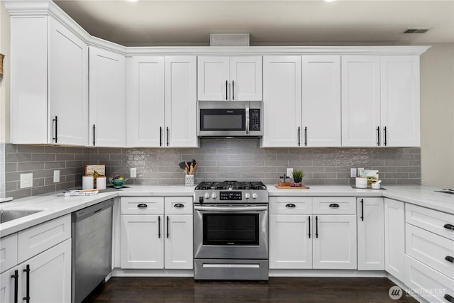 814 9th St SW, Puyallup, WA 98371 - kitchen with appliances with stainless steel finishes, white cabinets, dark wood-style floors, and decorative backsplash