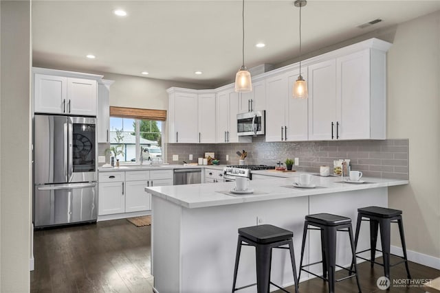 814 9th St SW, Puyallup, WA 98371 - kitchen featuring appliances with stainless steel finishes, a peninsula, white cabinets, pendant lighting, and recessed lighting