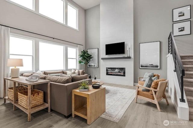 13212 164th Ave SE Unit 207, Renton, WA 98059 - living area featuring a towering ceiling, stairs, a glass covered fireplace, and light wood finished floors