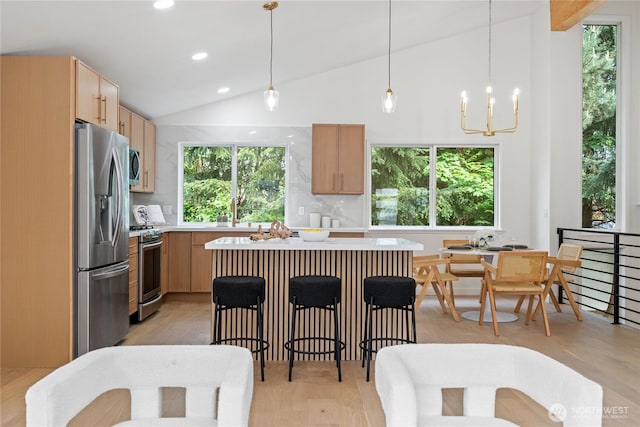 13652 99th Ave NE, Kirkland, WA 98034 - kitchen featuring appliances with stainless steel finishes, light countertops, vaulted ceiling, backsplash, and light brown cabinetry