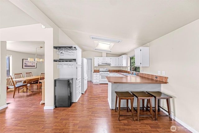 2366 Northshore Rd, Bellingham, WA 98226 - kitchen featuring white appliances, a peninsula, wood finished floors, white cabinets, and a breakfast bar
