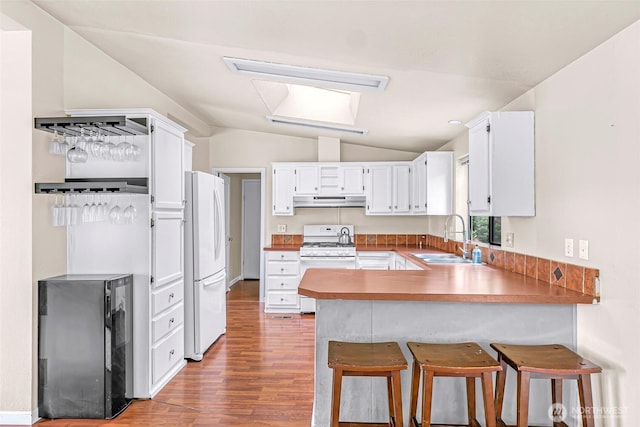 2366 Northshore Rd, Bellingham, WA 98226 - kitchen featuring white appliances, under cabinet range hood, a peninsula, vaulted ceiling, and wood finished floors