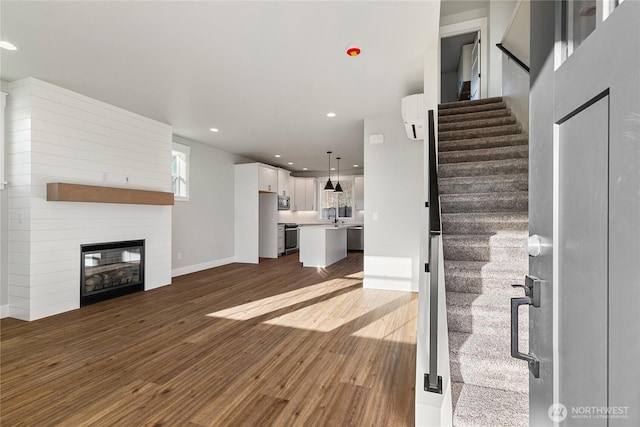 2630LOT12 Sievers Way, Ferndale, WA 98248 - unfurnished living room with dark wood-style flooring, recessed lighting, stairs, a wall unit AC, and a large fireplace