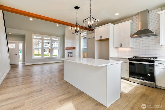 2632LOT13 Sievers Way, Ferndale, WA 98248 - kitchen with stainless steel gas range oven, wall chimney range hood, light wood-style flooring, a large fireplace, and backsplash