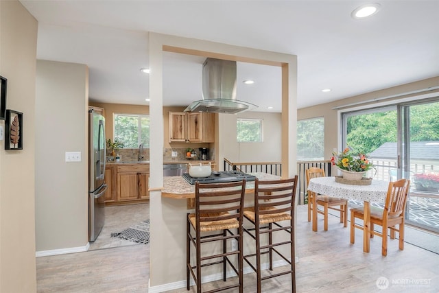 110 S 198th Pl, Des Moines, WA 98148 - kitchen with island exhaust hood, appliances with stainless steel finishes, light wood-type flooring, plenty of natural light, and recessed lighting