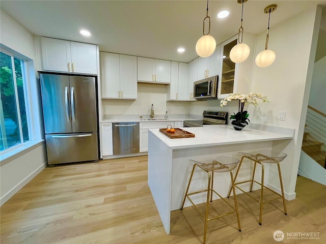746 N 88th St, Seattle, WA 98103 - kitchen featuring appliances with stainless steel finishes, light countertops, a peninsula, white cabinets, and recessed lighting