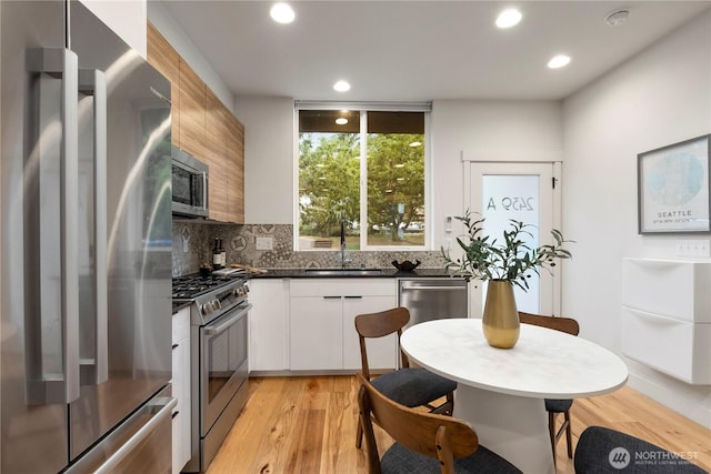 2439 NW 61st St Unit A, Seattle, WA 98107 - kitchen with appliances with stainless steel finishes, dark countertops, tasteful backsplash, light wood finished floors, and recessed lighting
