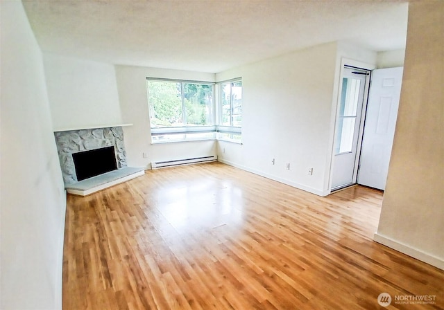 510 S 325th St Unit 19G, Federal Way, WA 98003 - unfurnished living room featuring baseboard heating, wood finished floors, and a stone fireplace