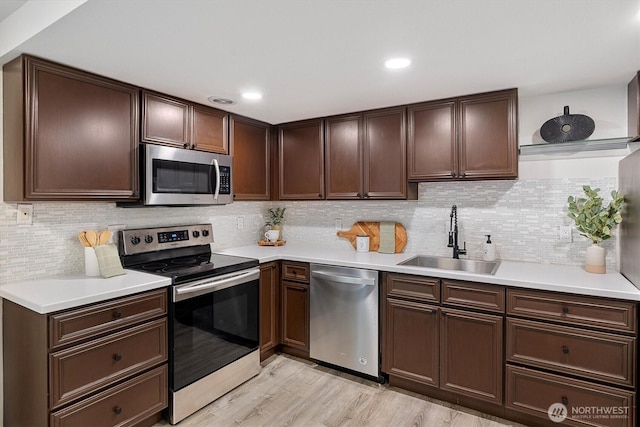 12718 NE 120th St Unit J-2, Kirkland, WA 98034 - kitchen featuring appliances with stainless steel finishes, light countertops, decorative backsplash, light wood-type flooring, and dark brown cabinets