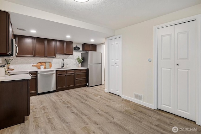 12718 NE 120th St Unit J-2, Kirkland, WA 98034 - kitchen with appliances with stainless steel finishes, dark brown cabinetry, light wood-style flooring, light countertops, and recessed lighting