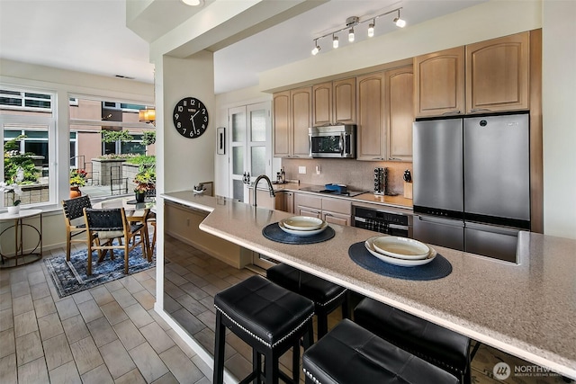 1900 Alaskan Way Unit 116, Seattle, WA 98121 - kitchen with appliances with stainless steel finishes, a kitchen bar, tasteful backsplash, wine cooler, and light countertops