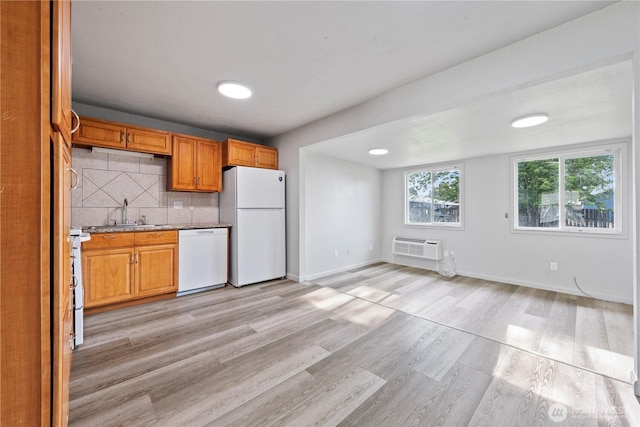 325 S 8th Ave, Othello, WA 99344 - kitchen featuring white appliances, light wood-style floors, backsplash, a wall mounted AC, and brown cabinetry