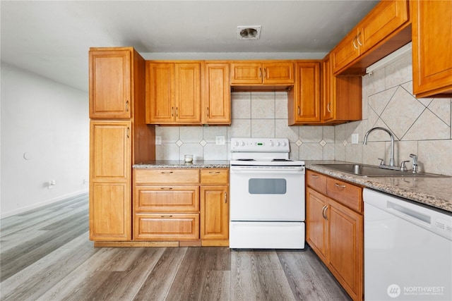 325 S 8th Ave, Othello, WA 99344 - kitchen featuring white appliances, wood finished floors, backsplash, brown cabinets, and light stone counters