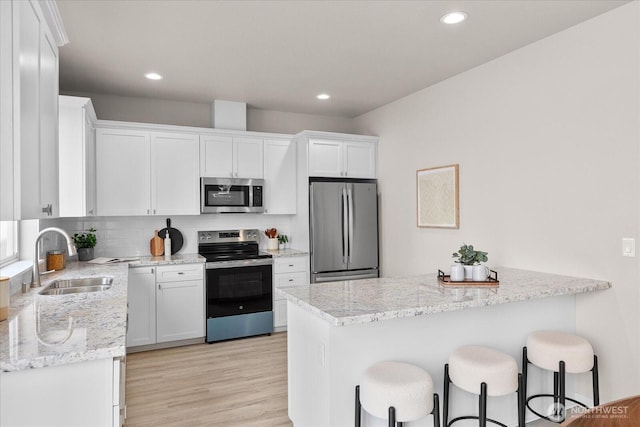 711 S 96th St, Tacoma, WA 98444 - kitchen featuring appliances with stainless steel finishes, white cabinets, a breakfast bar, a peninsula, and recessed lighting