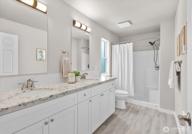 711 S 96th St, Tacoma, WA 98444 - full bath with wood finished floors, double vanity, curtained shower, and tasteful backsplash
