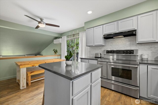 35632 158th St SE, Sultan, WA 98294 - kitchen with range with two ovens, under cabinet range hood, a wall mounted AC, dark countertops, and decorative backsplash